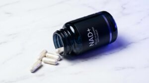 Cápsulas de NAD+ en frasco de vidrio oscuro sobre superficie de mármol